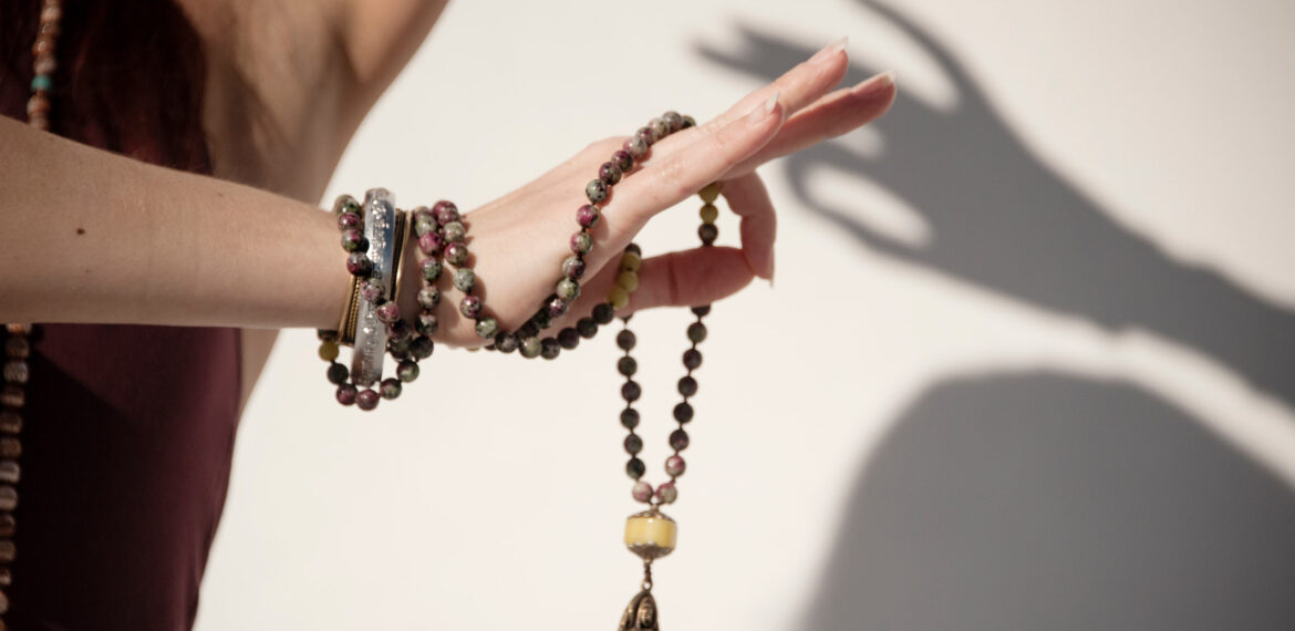 The elegant hand of a woman holding a mala yoga prayer bead neck The elegant hand of a woman holding a mala yoga prayer bead neck