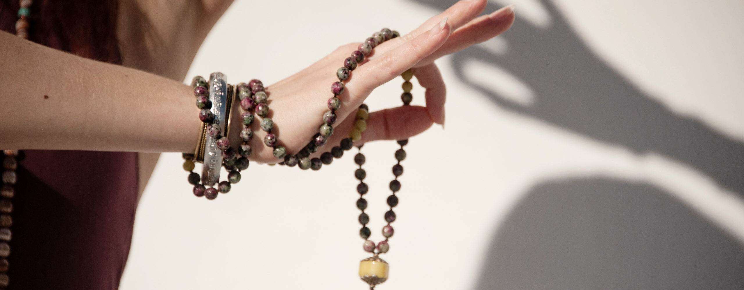 The elegant hand of a woman holding a mala yoga prayer bead neck