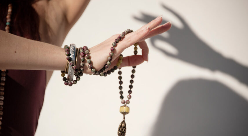 The elegant hand of a woman holding a mala yoga prayer bead neck